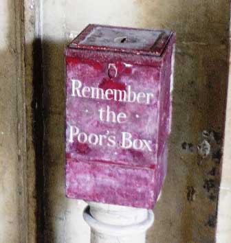 A red box that has the words Remember the Poors Box painted on it in white letters.