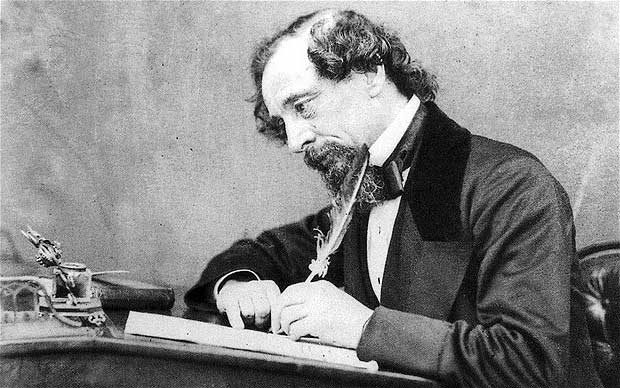 Charles Dickens writing at his desk.