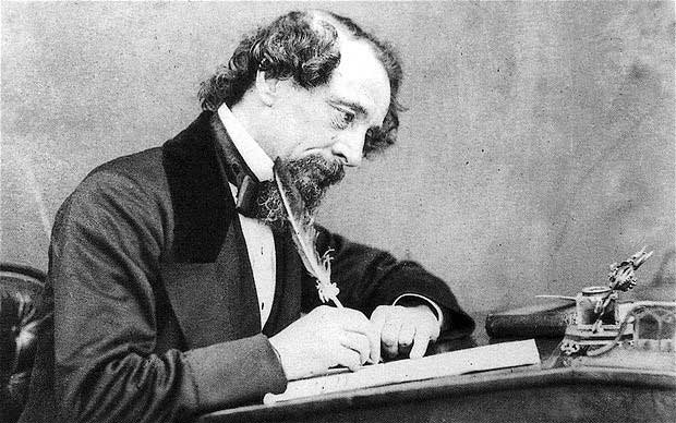 Charles Dickens writing at his desk.