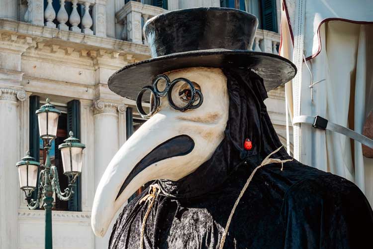 A man wearing a plague mask that has a beak.