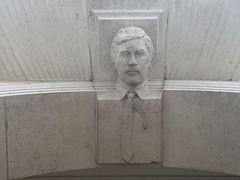 The seventh face a man with a carved stone tie.