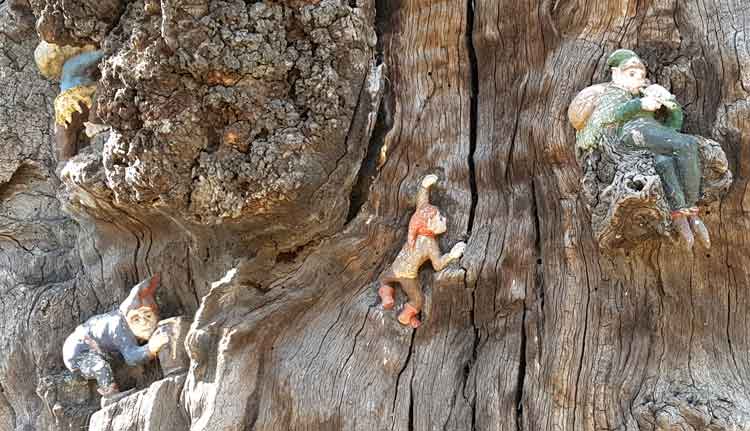 Two figures climb up the tree whilst a third plays on a horn.