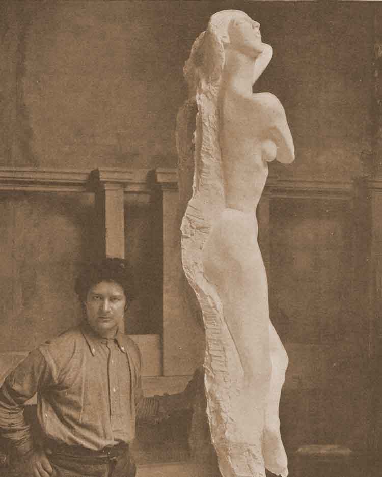 A photograph showing Jacob Epstein working on one of the statues.