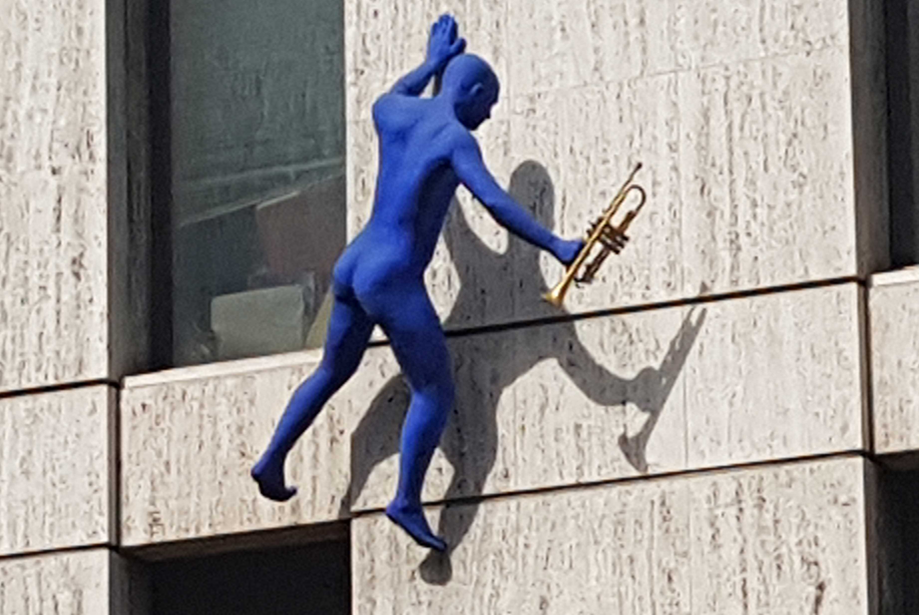 One of the blue figures climbing up the wall of Maya House.