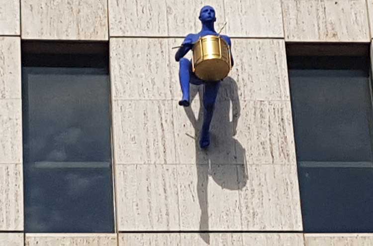 The third blue figure playing a drum.